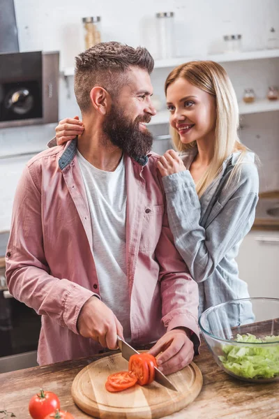 Cheerful couple preparing dinner in kitchen — Stock Photo