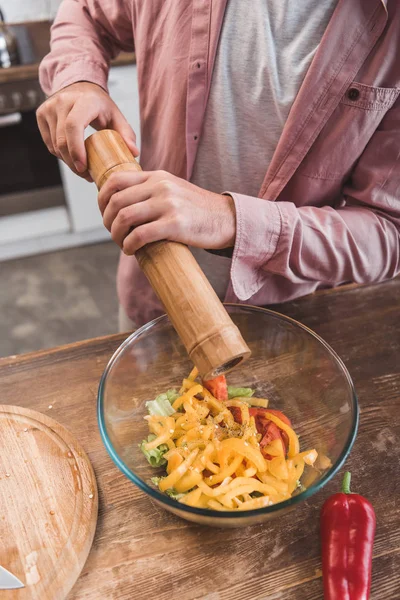 Cropped view of man salting salad in glass bowl — Stock Photo