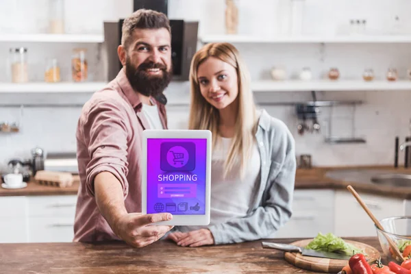 Sonriente pareja sosteniendo tableta digital con aplicación de compras en línea en la pantalla - foto de stock