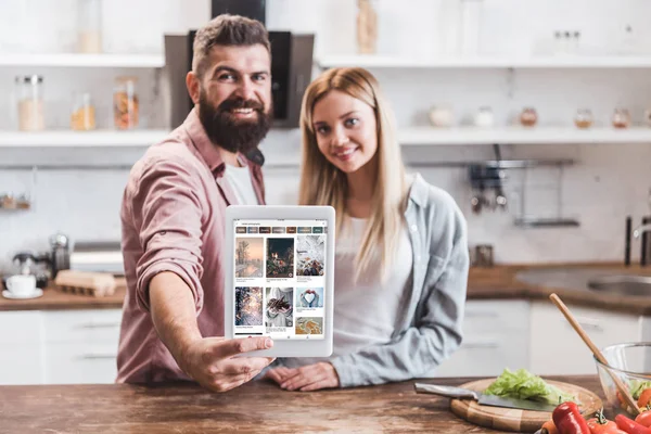 Couple holding digital tablet with pinterest app on screen at kitchen — Stock Photo
