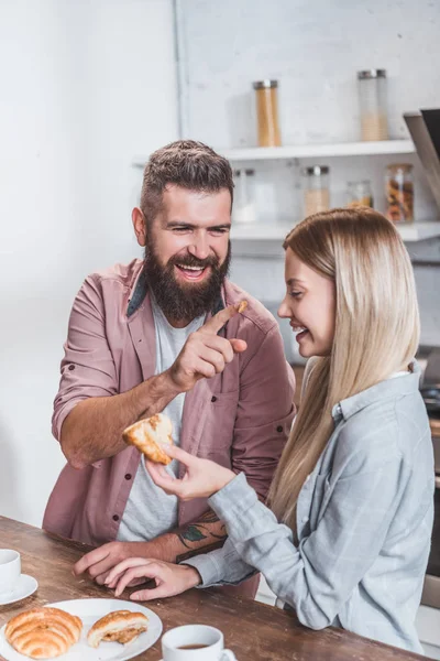 Sonriente pareja divirtiéndose durante el desayuno en la mañana - foto de stock