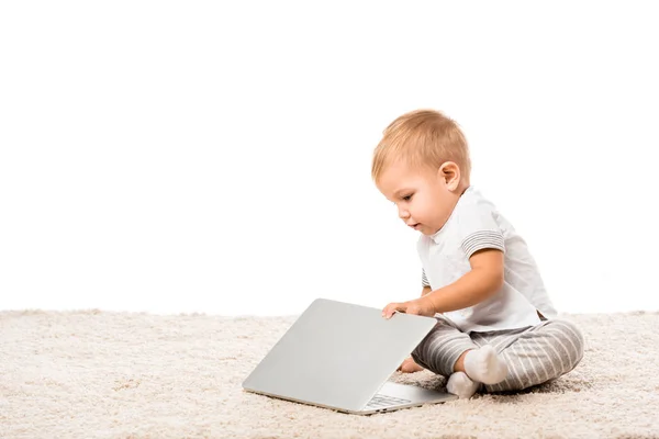 Tout-petit garçon assis sur le tapis et fermeture ordinateur portable isolé sur blanc — Photo de stock