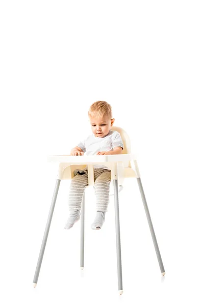 Niedliche Kleinkind sitzt im Hochstuhl isoliert auf weiß — Stockfoto