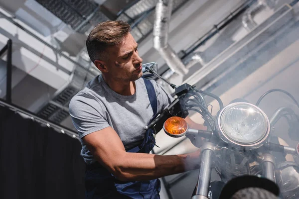 Handsome adult mechanic repairing motorcycle in garage — Stock Photo