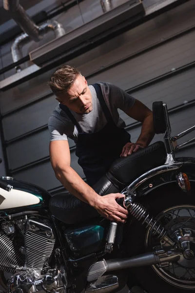 Serious mechanic checking back wheel in garage — Stock Photo