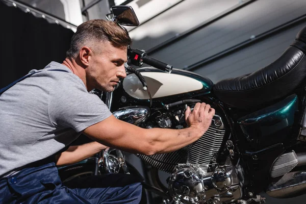 Mechanic checking motorbike engine in garage — Stock Photo