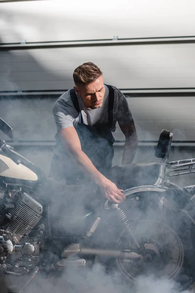 Mechanic checking motorbike engine in garage — Stock Photo