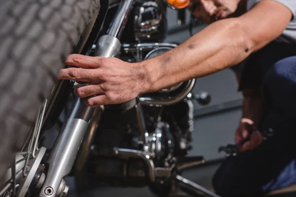 Closeup of mechanic fixing motorbike front wheel in garage — Stock Photo