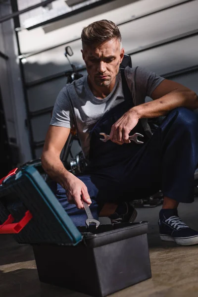 Mechaniker sitzt mit Werkzeugkiste auf dem Boden in Garage — Stockfoto