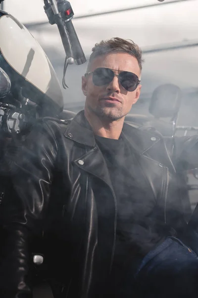 Klassischer Motorradfahrer mit schwarzer Sonnenbrille mit Motorrad in Garage — Stockfoto