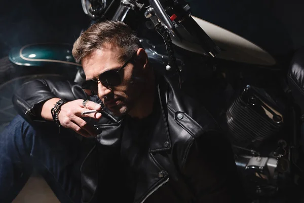 Gutaussehender Mann mit Sonnenbrille sitzt mit Motorrad in Garage — Stockfoto