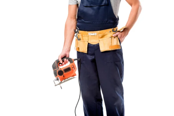 Vue recadrée du charpentier avec ceinture à outils tenant la scie électrique de fret isolé sur blanc — Photo de stock