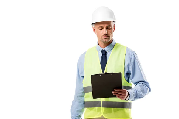 Focused engineer in helmet looking at clipboard isolated on white — Stock Photo