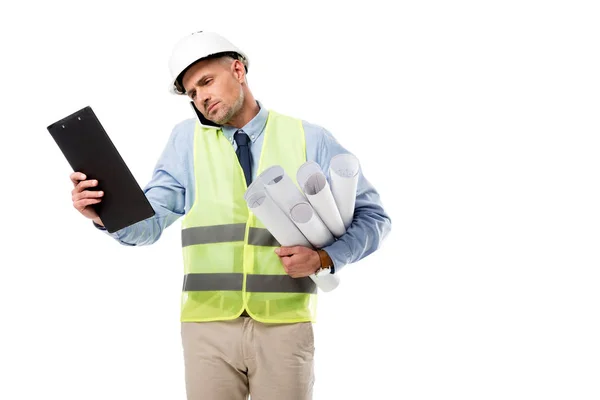 Handsome engineer holding blueprints, talking on smartphone and looking at clipboard isolated on white — Stock Photo
