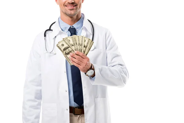 Vista recortada de sonriente médico sosteniendo billetes de dólar aislados en blanco, concepto de seguro de salud - foto de stock