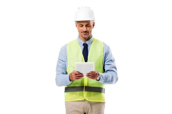Engineer in helmet smiling and using digital tablet isolated on white — Stock Photo