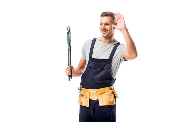 Trabajador feliz sosteniendo la llave de tubo, saludando y mirando hacia otro lado aislado en blanco - foto de stock