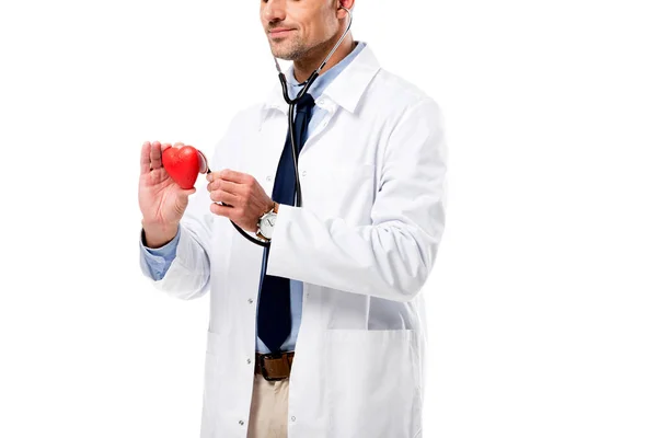 Cropped view of doctor examining heart model with stethoscope isolated on white, heart healthcare concept — Stock Photo