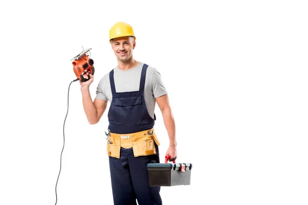 Trabajador de la construcción mirando la cámara y la caja de herramientas con sierra eléctrica aislada en blanco - foto de stock