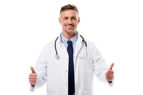 Lächelnder Arzt in weißem Mantel mit Stethoskop, der Daumen hoch Zeichen isoliert auf weiß — Stockfoto