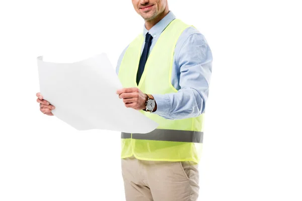 Vista ritagliata di ingegnere sorridente in giubbotto di sicurezza tenendo cianografia isolata su bianco — Foto stock