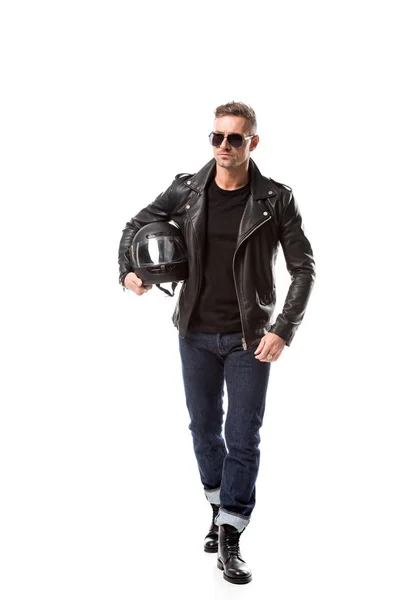 Впевнений чоловік у шкіряній куртці та сонцезахисних окулярах тримає мотоциклетний шолом ізольовано на білому — стокове фото