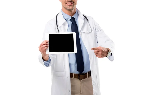 Ausgeschnittene Ansicht eines lächelnden Arztes, der mit dem Finger auf ein digitales Tablet mit leerem Bildschirm zeigt, isoliert auf weiß — Stockfoto