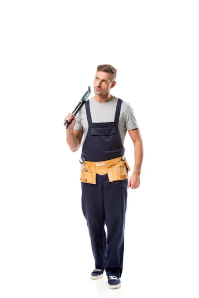 Serious plumber in overalls holding pipe wrench isolated on white — Stock Photo