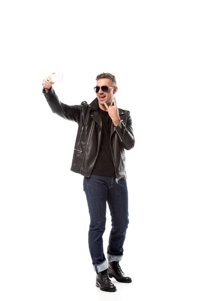 Stylischer erwachsener Mann in Lederjacke zeigt Rockzeichen und macht Selfie auf Smartphone isoliert auf weiß — Stockfoto