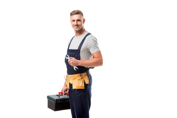 Beau travailleur tenant boîte à outils, clé et regardant la caméra isolée sur blanc — Photo de stock