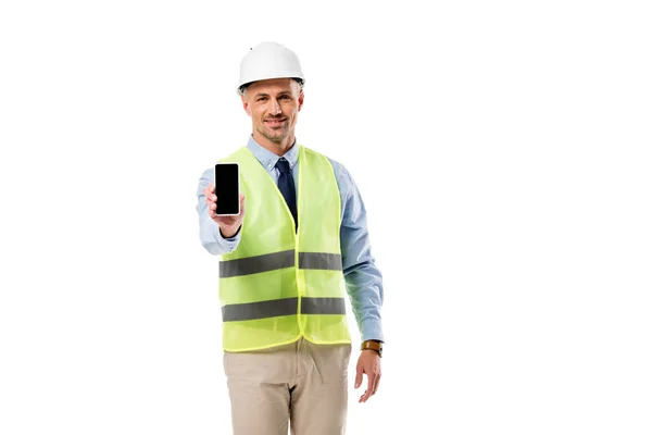 Ingeniero sonriente mirando a la cámara y sosteniendo el teléfono inteligente con pantalla en blanco aislado en blanco - foto de stock