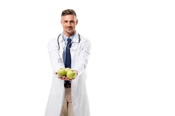 Smiling doctor looking at camera and holding fresh apples isolated on white, healthy eating concept — Stock Photo