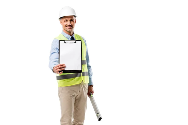 Ingeniero sonriente sujetando portapapeles con hoja en blanco y nivel de espíritu aislado en blanco - foto de stock
