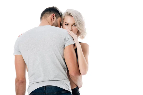 Hermosa mujer rubia mirando a la cámara y abrazando al hombre aislado en blanco - foto de stock