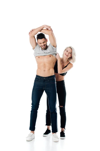 Sorrindo jovem mulher tirando t-shirt de namorado bonito isolado no branco — Fotografia de Stock