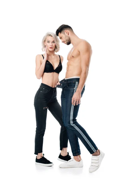 Fidanzata sorpresa giocosamente toccando jeans fidanzato e guardando la fotocamera isolata su bianco — Foto stock