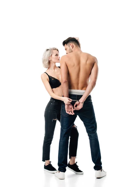 Красива молода жінка тримає чоловіка за наручники ізольовано на білому — стокове фото