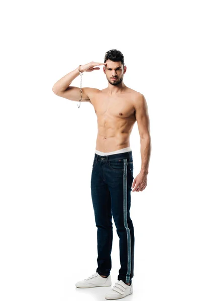 Handsome man with handcuffs on hand looking at camera and saluting isolated on white — Stock Photo