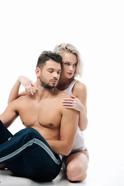 Donna seducente abbracciando delicatamente l'uomo senza camicia e guardando lontano isolato sul bianco — Foto stock