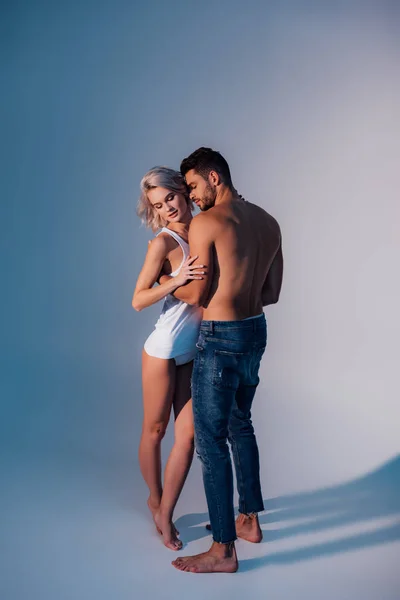 Hermosa pareja heterosexual abrazando sobre fondo azul oscuro - foto de stock