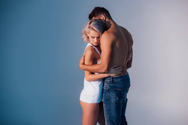 Joven pareja heterosexual abrazándose sobre fondo azul oscuro - foto de stock