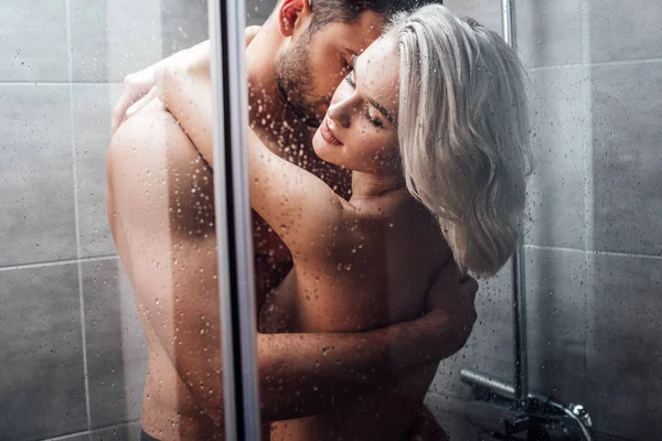 Beautiful naked heterosexual couple hugging and taking shower together — Stock Photo