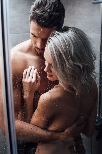 Schönes nacktes Paar, das sich leidenschaftlich umarmt und zusammen duscht — Stockfoto