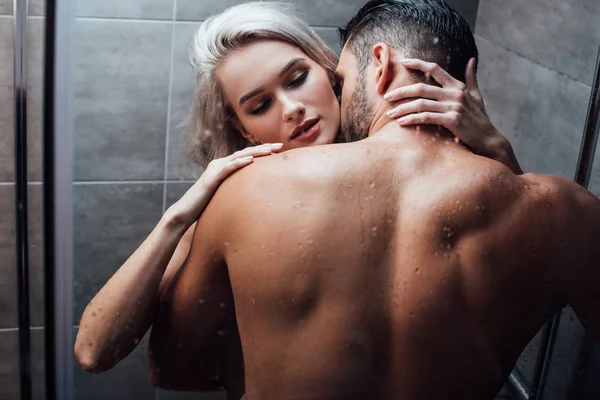 Affectionate heterosexual couple hugging and kissing while taking shower together — Stock Photo