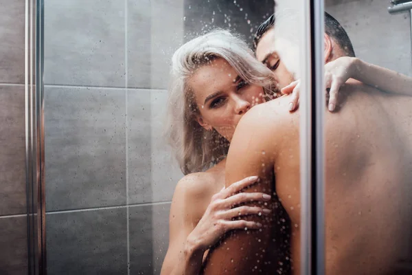 Passionate man embracing and kissing beautiful woman in shower — Stock Photo