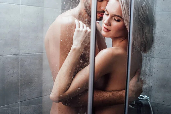 Man passionately embracing attractive woman in shower — Stock Photo