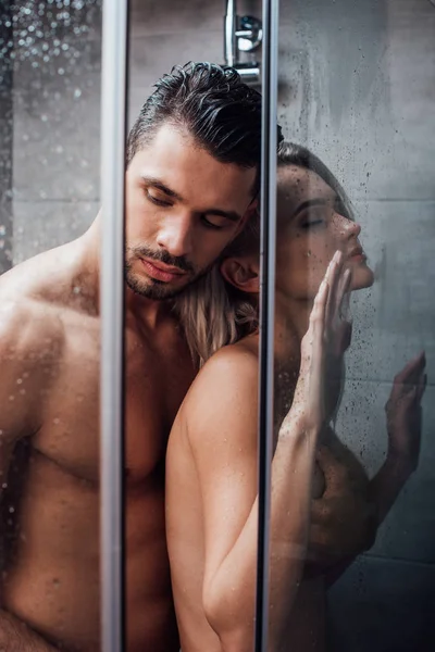 Beautiful naked couple embracing in passion and taking shower together — Stock Photo