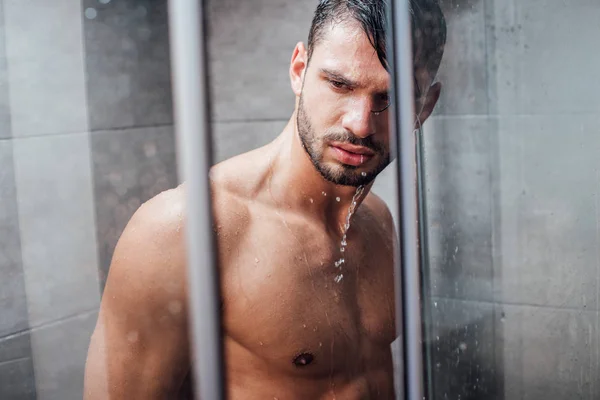 Guapo desnudo muscular hombre tomando ducha en cuarto de baño - foto de stock