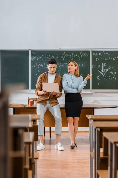 Selektiver Fokus männlicher Schüler und weiblicher Lehrer mit Laptop während des Unterrichts im Klassenzimmer — Stockfoto
