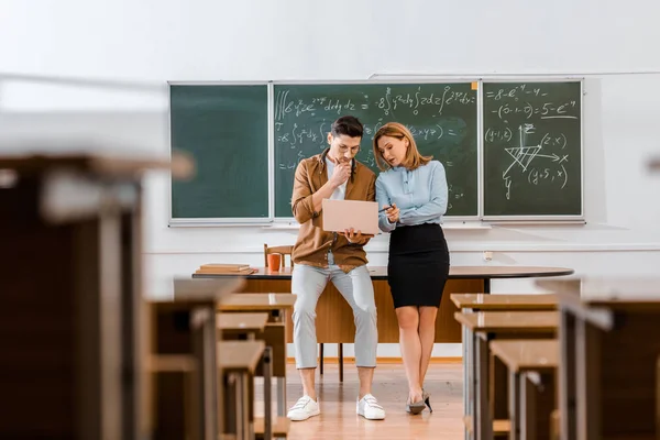 Jeune étudiant debout avec une enseignante et regardant ordinateur portable — Photo de stock